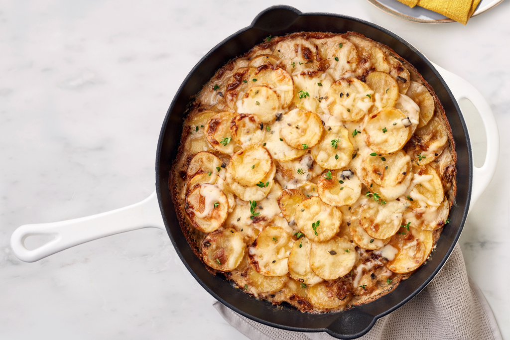 Pommes de terre dauphinoise et échalotes dans une poêle en fonte